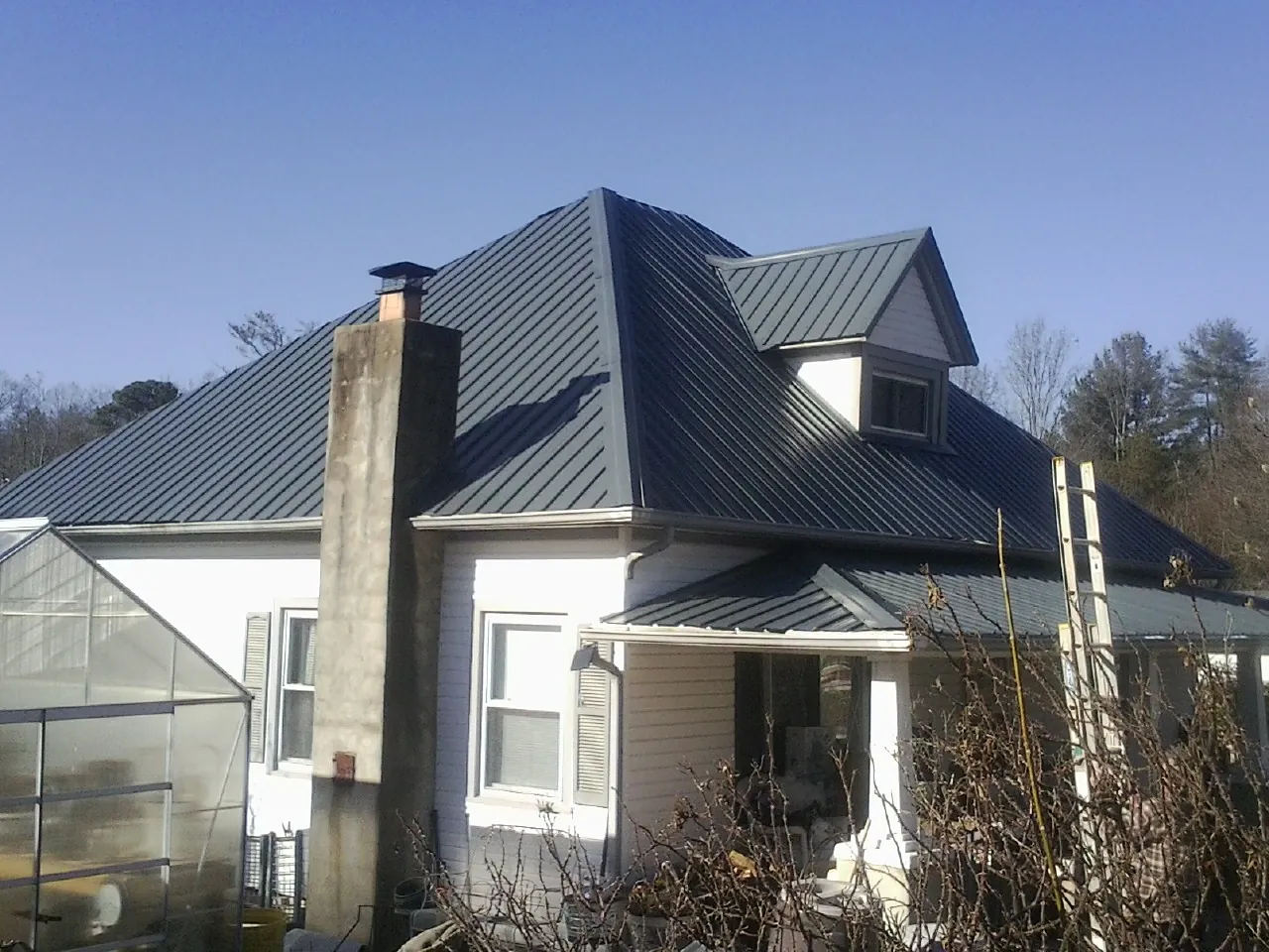 Dark blue standing seam metal roof on a white farmhouse with dormer — Slate & Tile Roof Repair by Roofing Brothers in Sugar Grove
