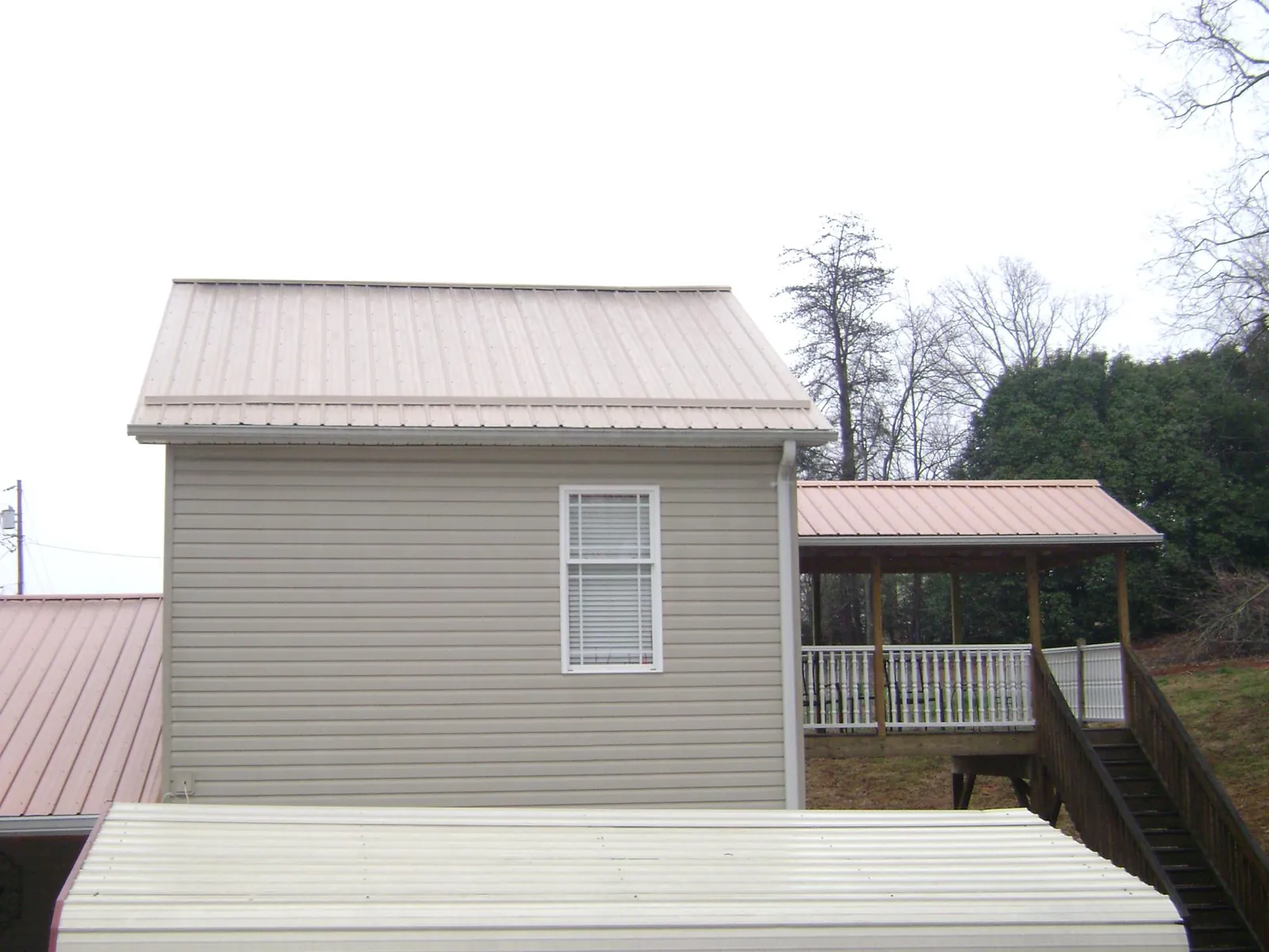 Tan metal roofs on a two story addition and attached porch, from a Roof Replacement job in Sugar Grove